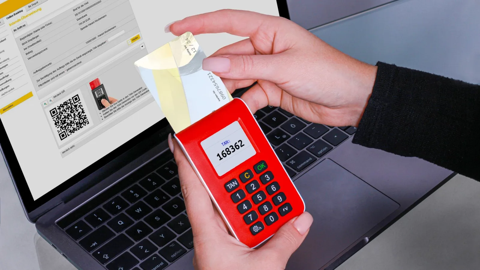 A hand holding a security key next to a laptop login screen