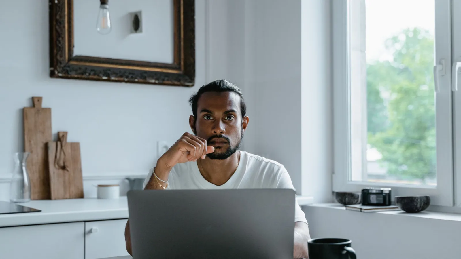 A person sitting at a desk, thinking while looking at a laptop screen